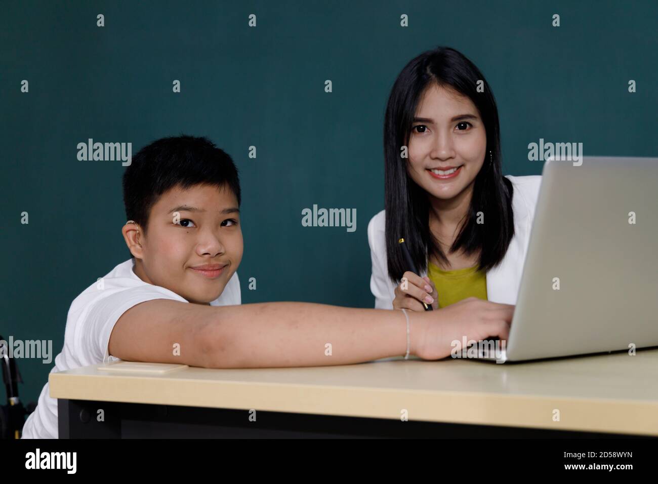 Un ragazzo asiatico studia utilizzando un computer portatile con il suo insegnante in classe. Foto Stock
