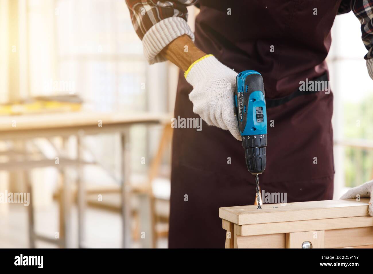 Falegname utilizzare un trapano elettrico su tavola di legno in officina di Falegnameria. Foto Stock