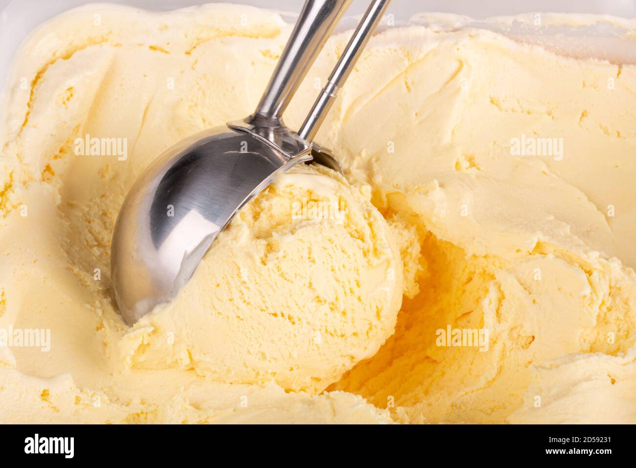 Primo piano di gelato alla vaniglia che viene ballato da una paletta meccanica. Foto Stock