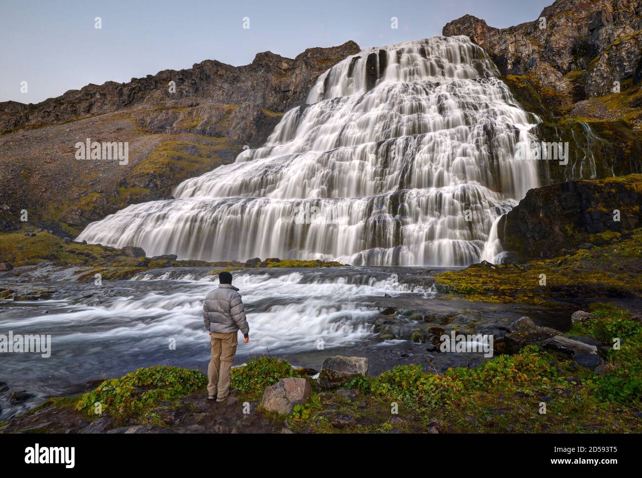 Vista posteriore di un uomo che guarda la cascata Dynjandi, Westfjords, Islanda del Nord, Islanda Foto Stock