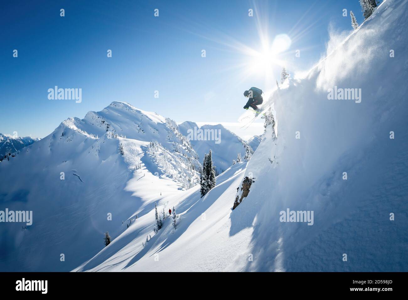 Sciatore a mezz'aria mentre gli heli del backcountry sciano nei Kootenays, British Columbia, Canada Foto Stock