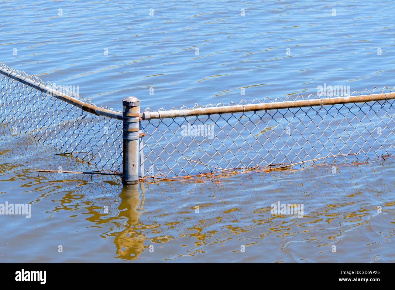 Una recinzione di collegamento di catena in acqua. L'acqua è la maggior parte del senso sulla recinzione. La recinzione presenta un leggero strato di ruggine in alcuni punti. Foto Stock
