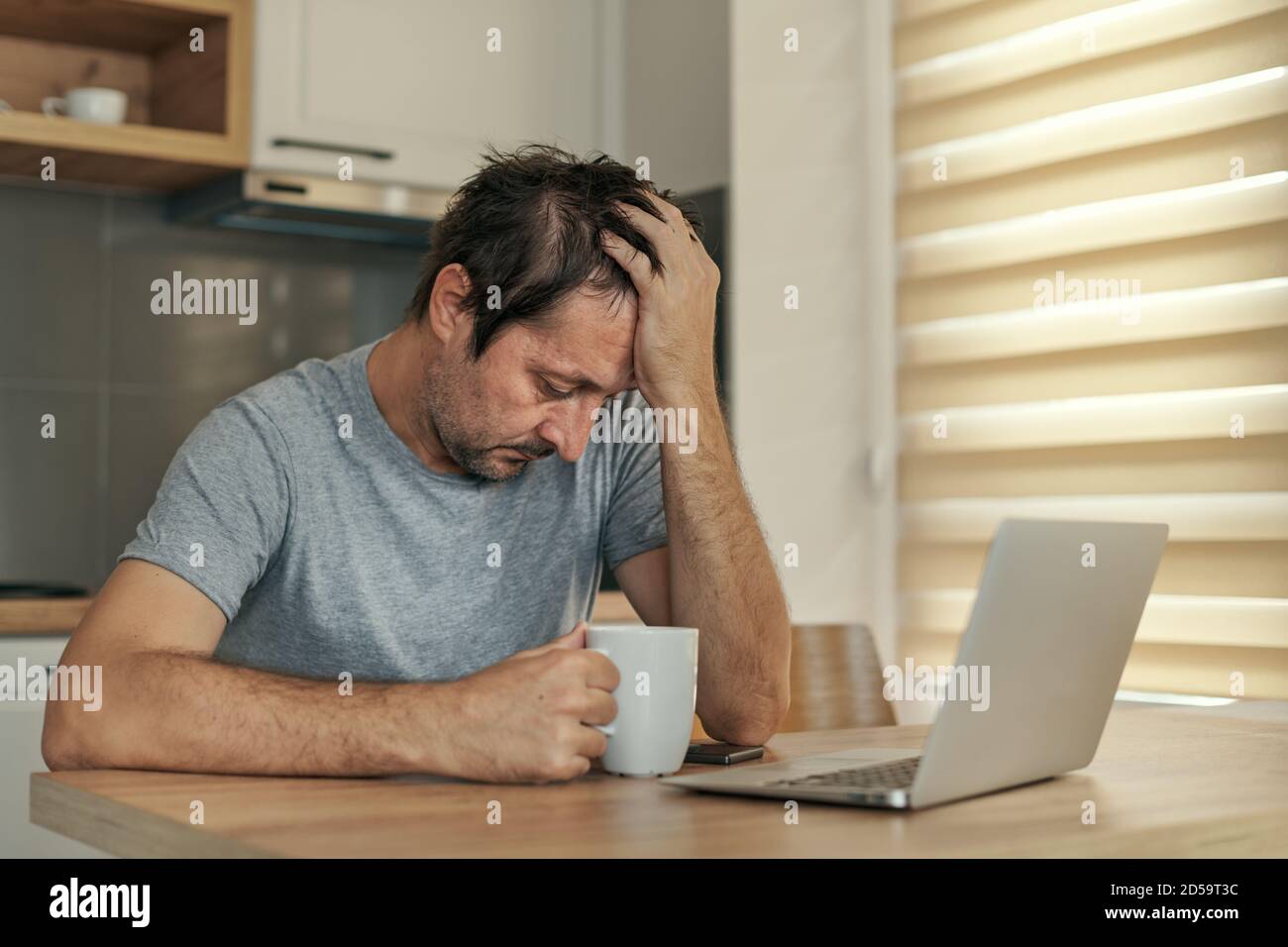 Freelancer deluso a casa ufficio avendo problemi di lavoro con la sua testa in mani, fuoco selettivo Foto Stock