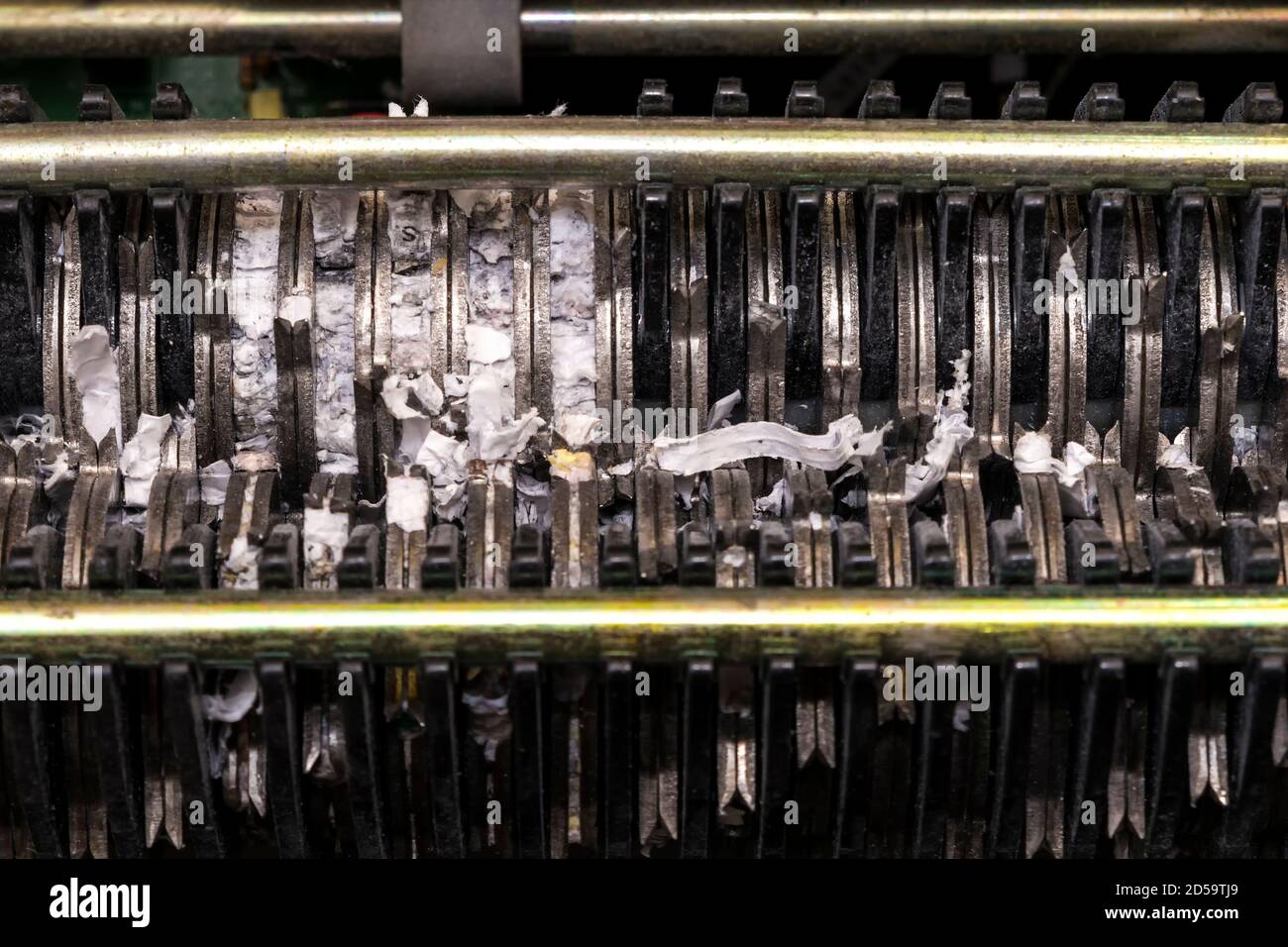 L'interno di un tritadocumenti. Il meccanismo di triturazione è visibile e vi sono frammenti di carta. Vista in primo piano. Foto Stock