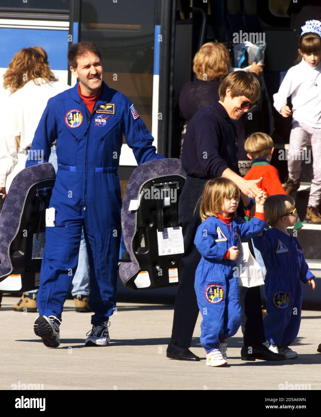 L'astronauta della Discovery dello Space Shuttle John Grunsfeld (L) porta i seggiolini per bambini mentre segue la sua famiglia mentre partono per Houston il 28 dicembre. La moglie di Grunsfeld, Carol, accompagna i figli a destra. La navetta e l'equipaggio di sette persone sono atterrati al Kennedy Space Center il 27 dicembre, concludendo una missione di otto giorni per riparare il telescopio spaziale Hubble. JLS Foto Stock