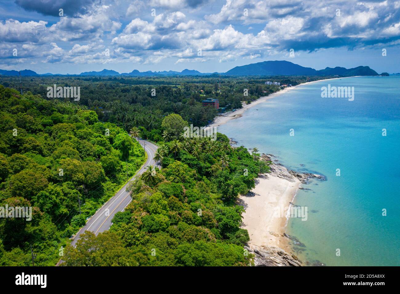 Vista aerea della strada tra palme da cocco e il grande oceano di giorno a Nakhon si Thammarat, Thailandia Foto Stock