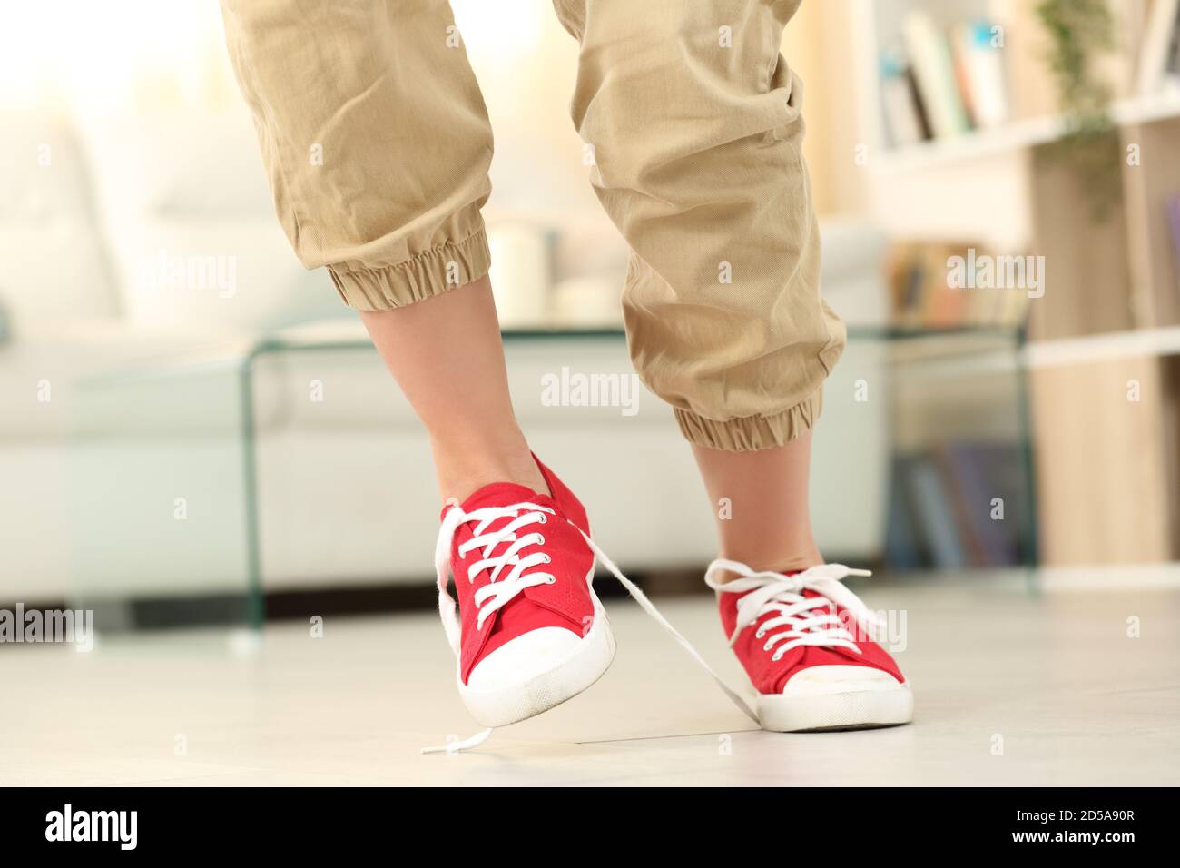 Vista frontale delle gambe di una donna che inciampano con le scarpe che camminano a casa Foto Stock