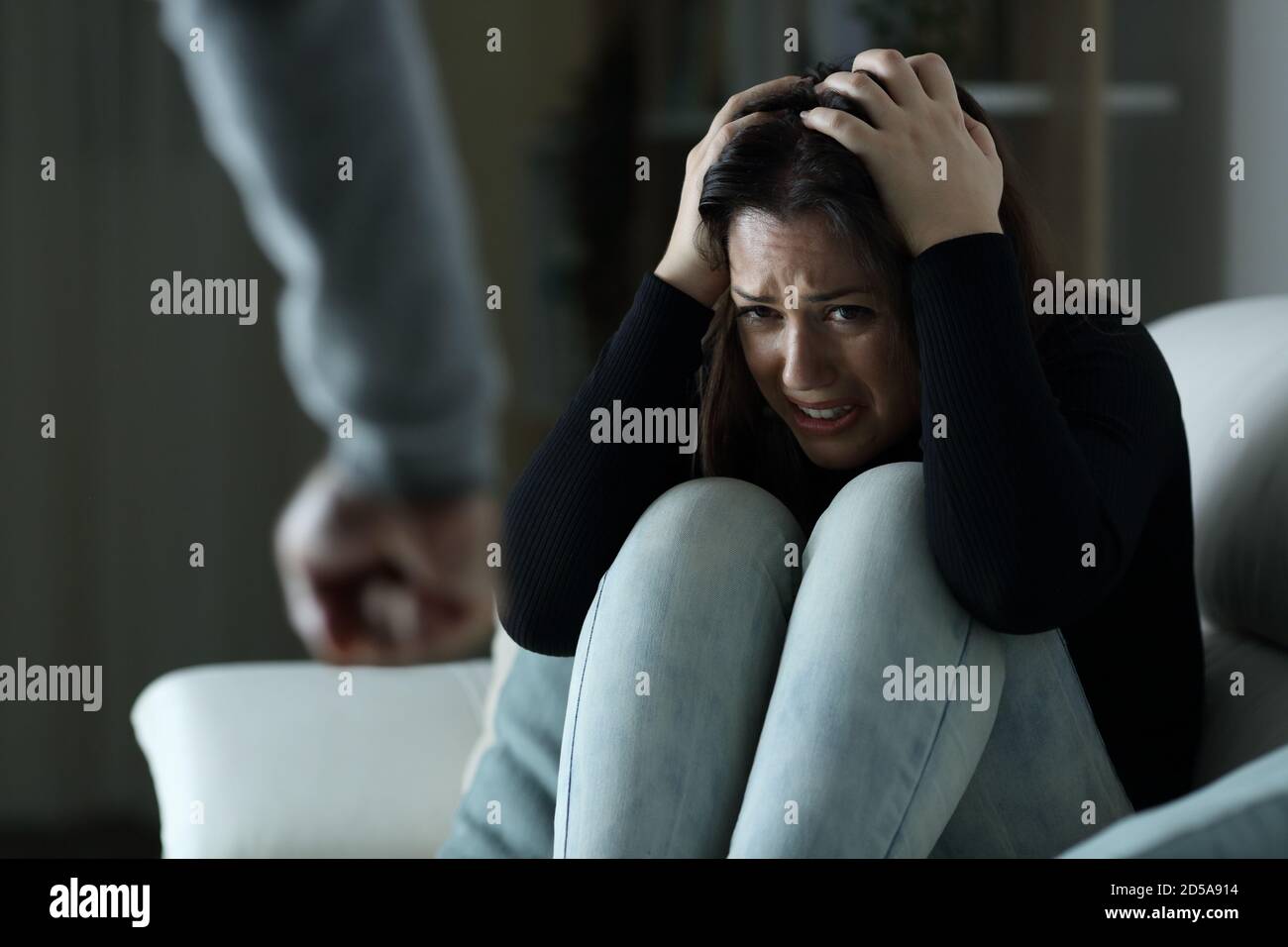 Temuta donna vittima di violenza di genere seduta su un divano di notte a casa Foto Stock