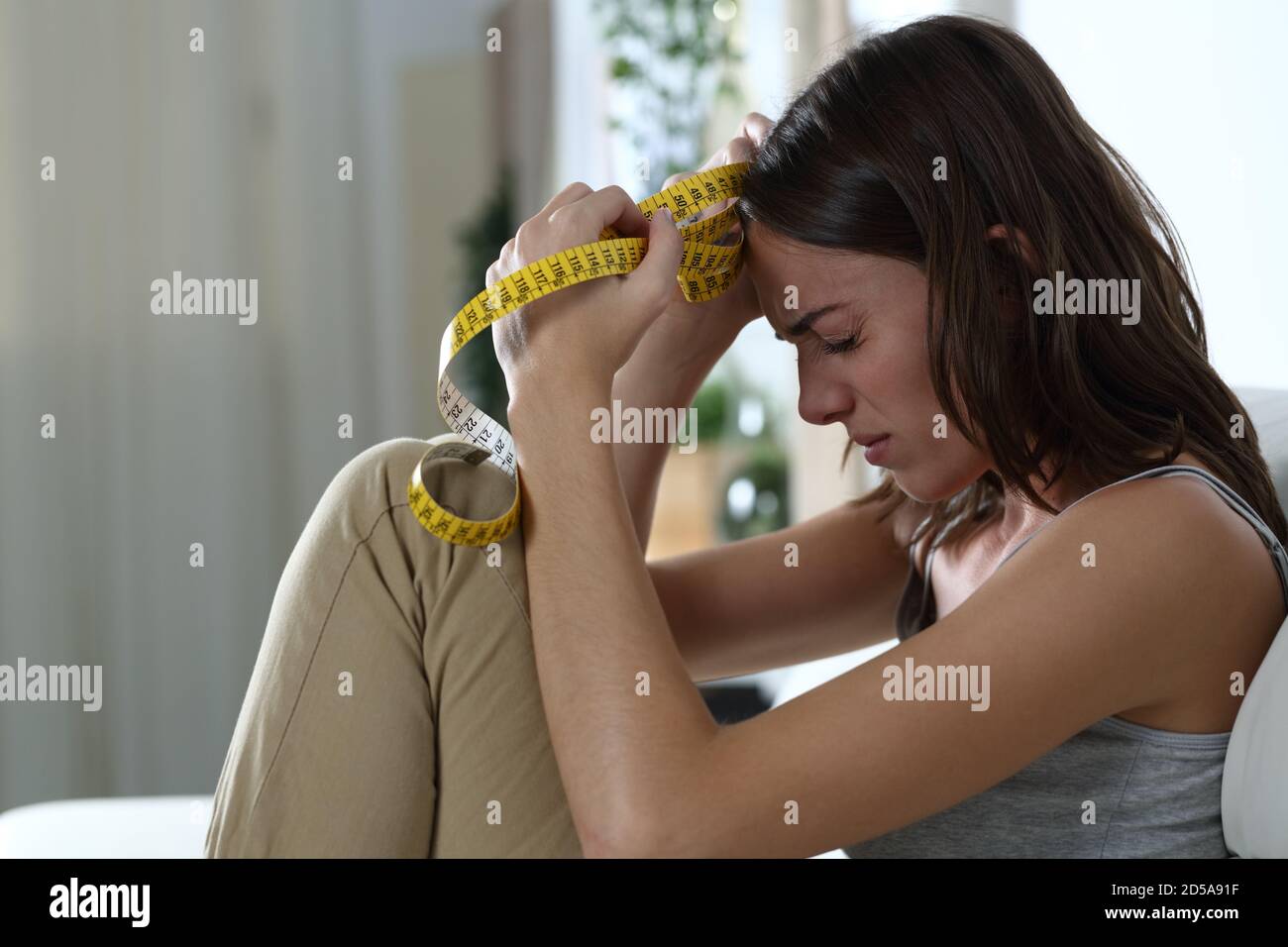 Profilo di una donna triste ossessionata dalla dieta lamentando la seduta a casa Foto Stock