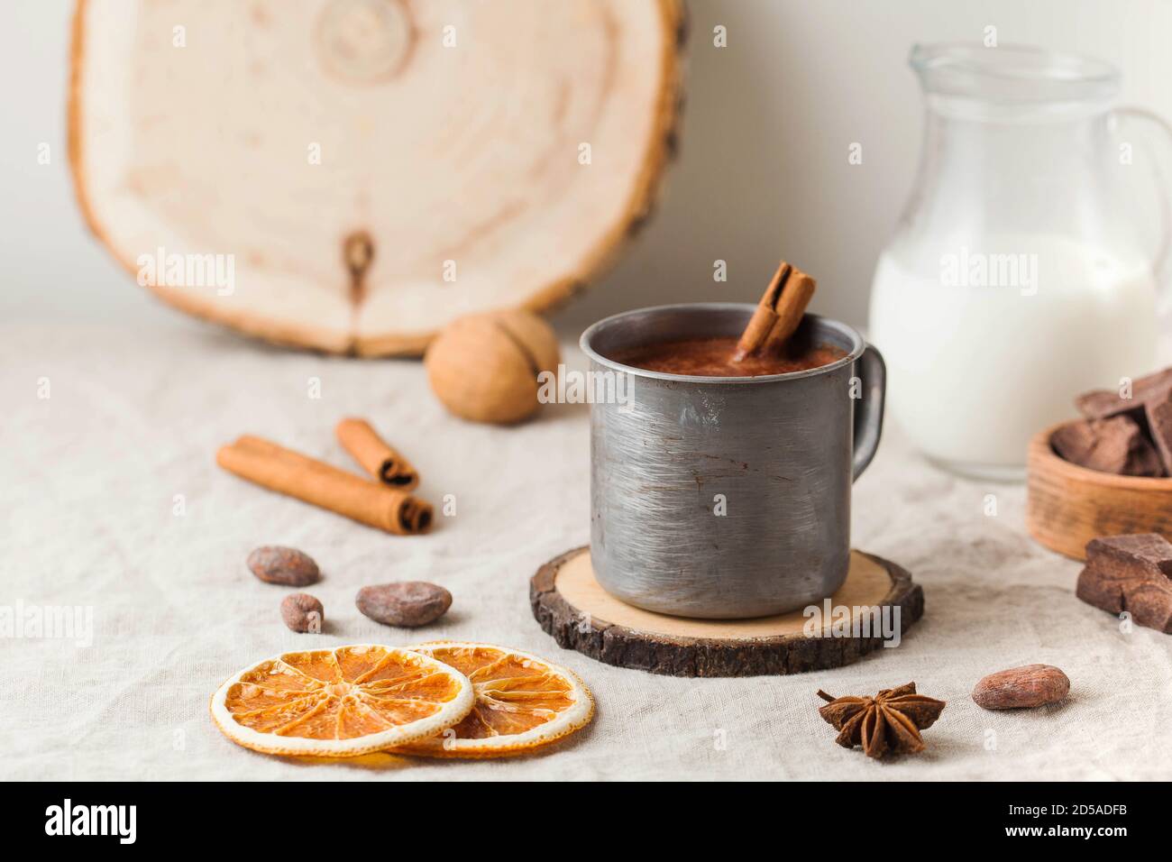 Cioccolata calda in una tazza di metallo con un bastoncino di cannella sulla tovaglia. Spazio di copia Foto Stock