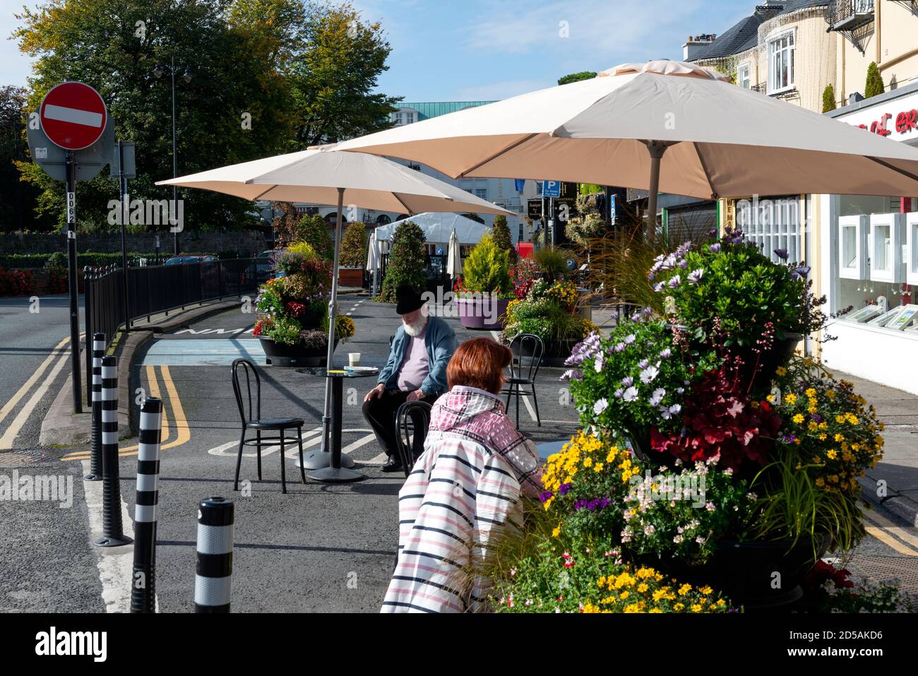 Persone social distancing in zona pedonale con grandi vasi di fiori a Killarney, Contea di Kerry, Irlanda Foto Stock