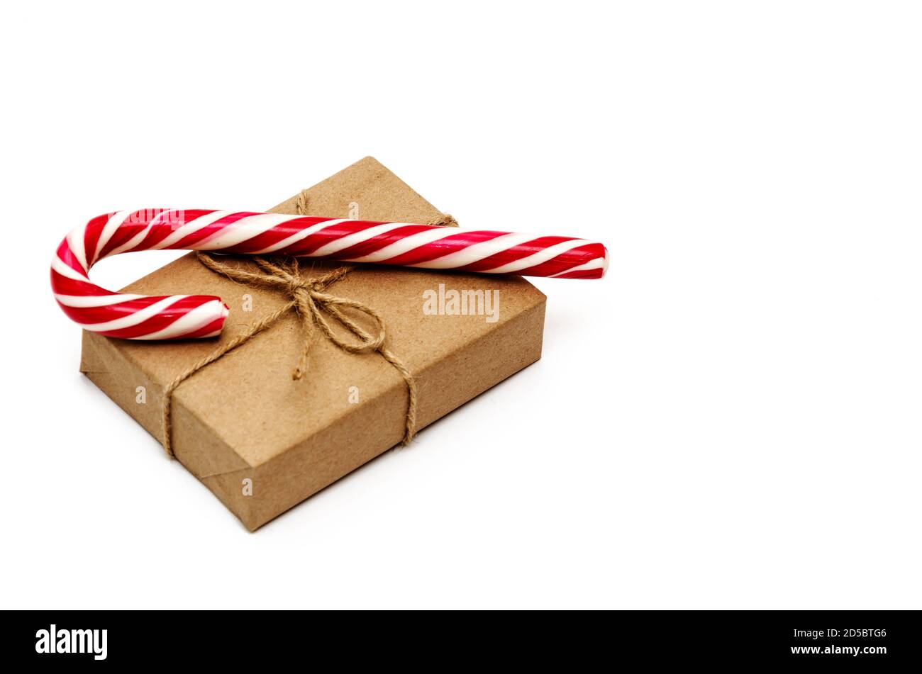Scatola regalo di Natale avvolta in carta kraft legata con spago e canna caramella su uno sfondo bianco. Concetto di Natale, inverno e Capodanno Foto Stock