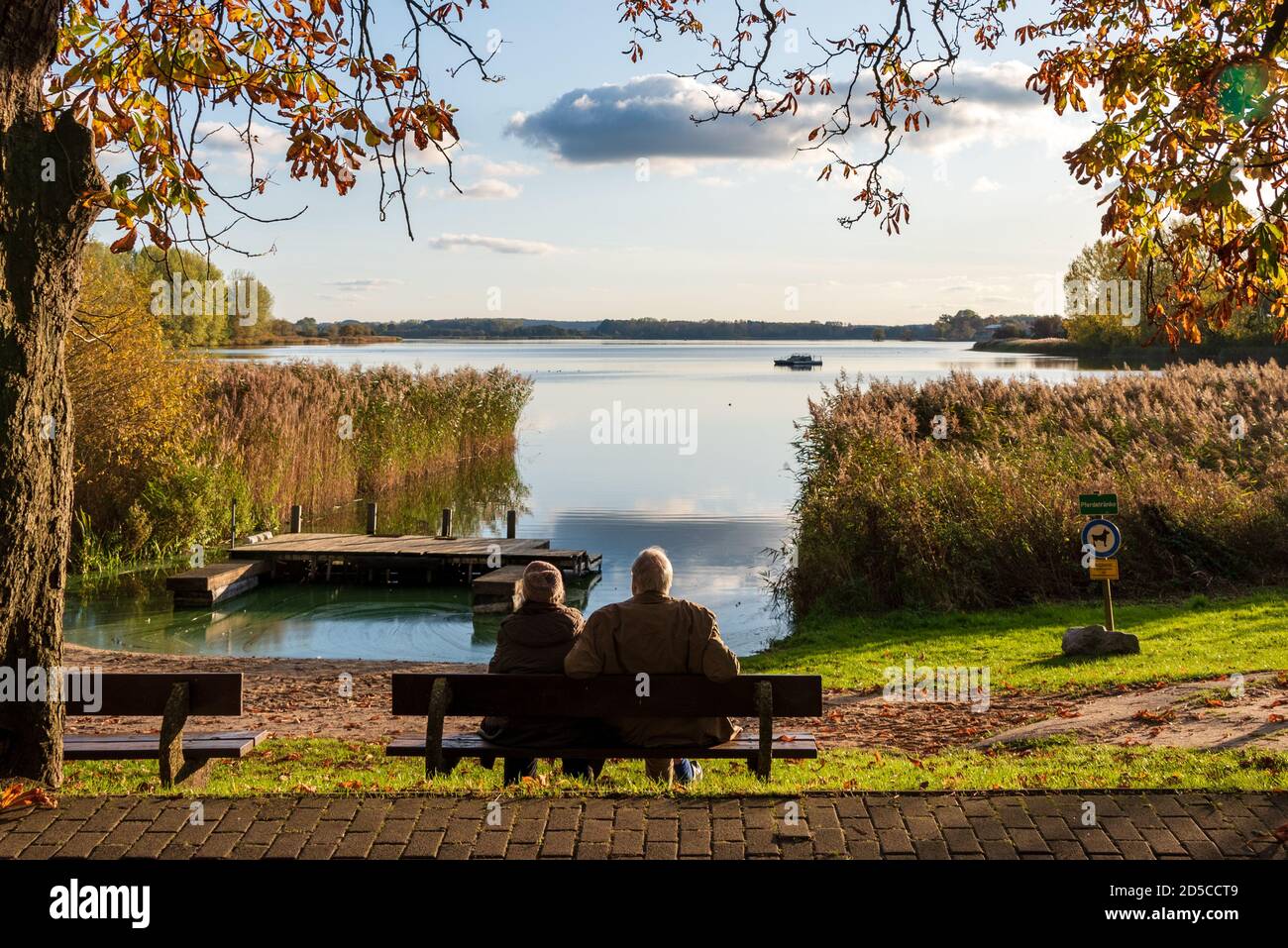 Herbstliche Stimmung am Passader See in Schleswig-Holstein, ein altes Ehepaar genißt die Herbstsonne Foto Stock