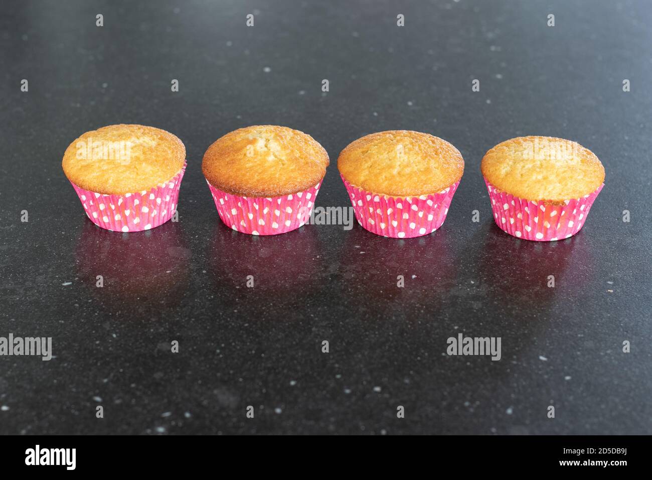 Cupcake al forno in casa su sfondo scuro, rosa con puntini Foto Stock