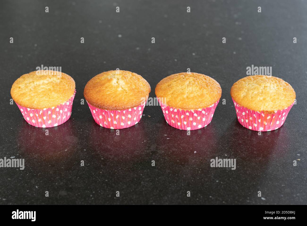 Cupcake al forno in casa su sfondo scuro, rosa con puntini Foto Stock