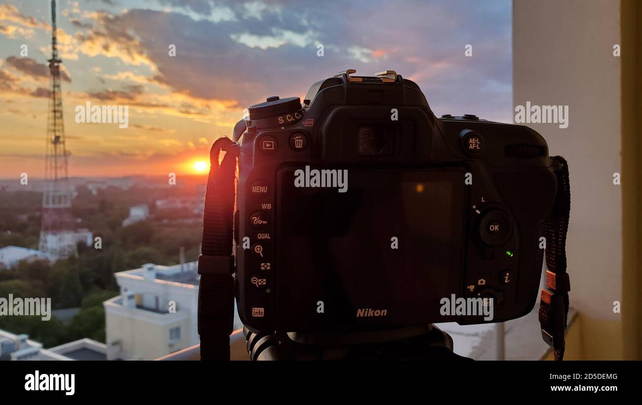 Odessa Ucraina - 08 27 2020: Fotocamera DSLR su treppiede spara il tramonto sulla città con cielo nuvoloso e sagoma sfocata della torre di comunicazione Foto Stock