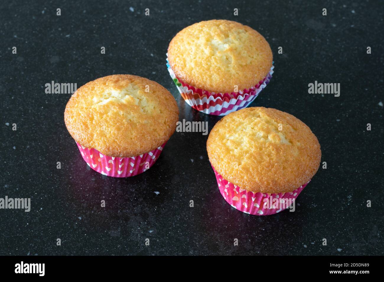 Cupcake al forno in casa su sfondo scuro, rosa con puntini Foto Stock