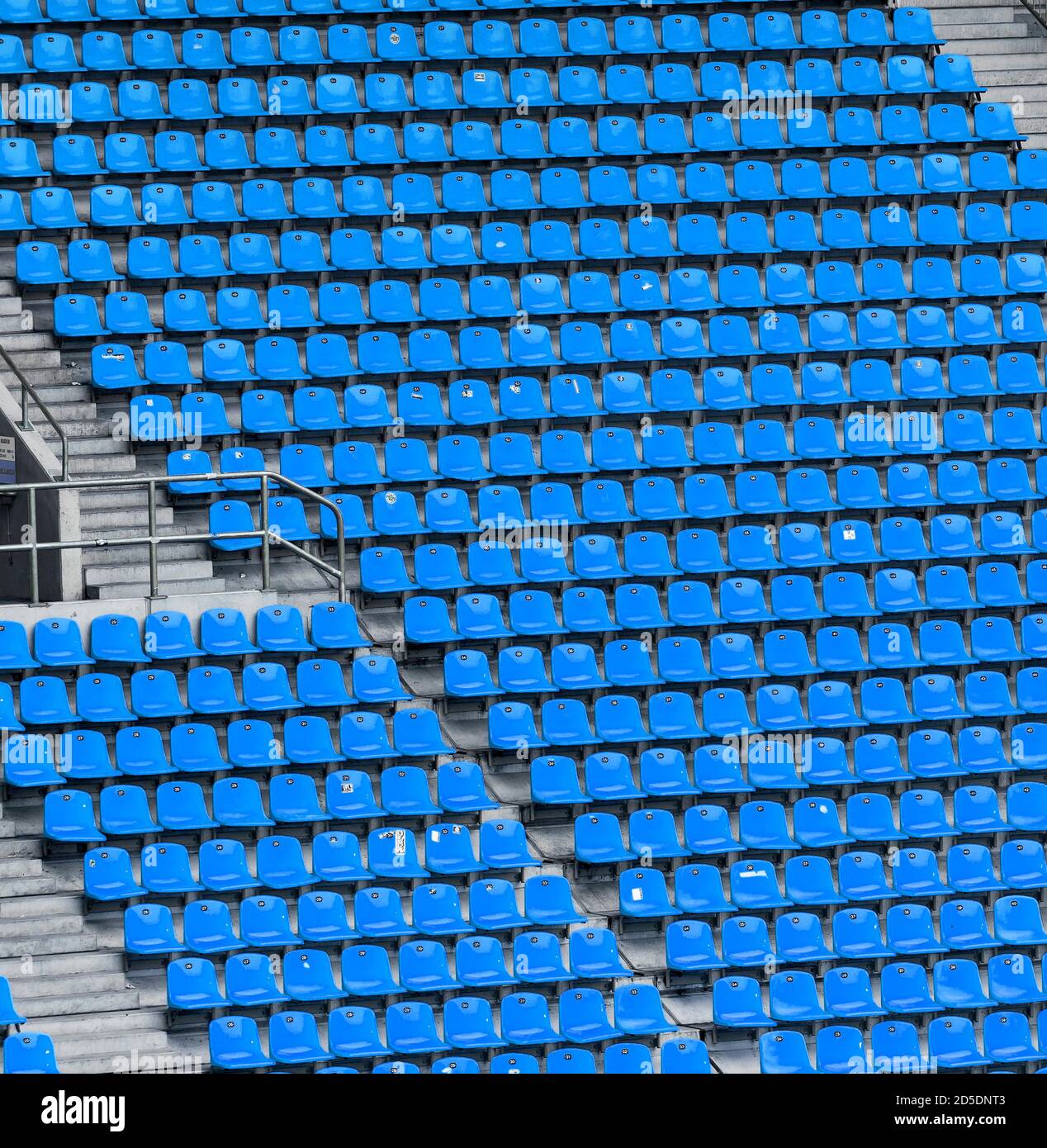 Molte file di posti a sedere blu in un grande stadio sportivo senza spettatori con scale in cemento. Foto Stock