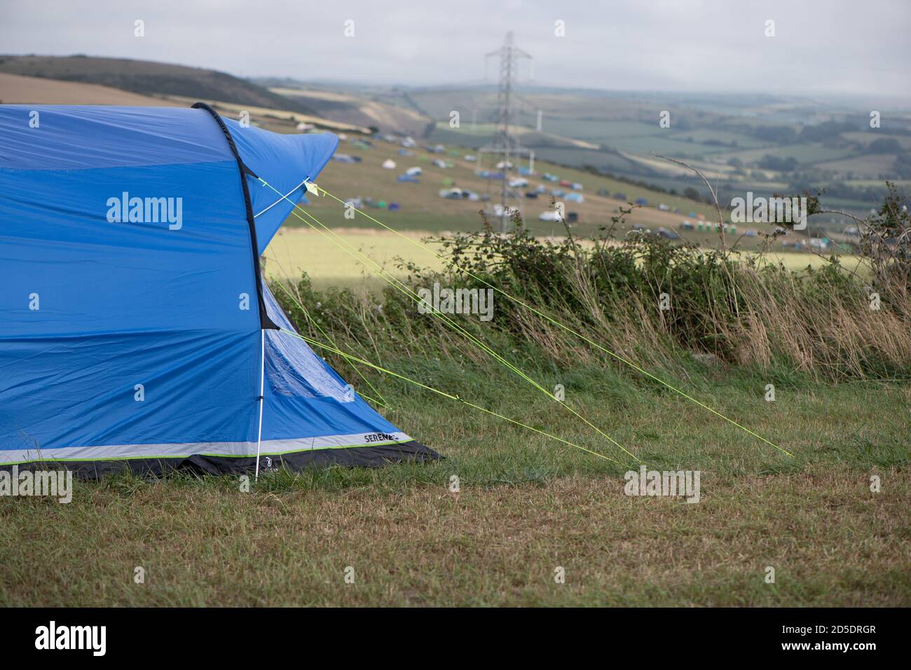 Una singola moderna tenda blu con diverse colture e angolazioni in un campo con spazio di copia da utilizzare in campeggio storie Foto Stock