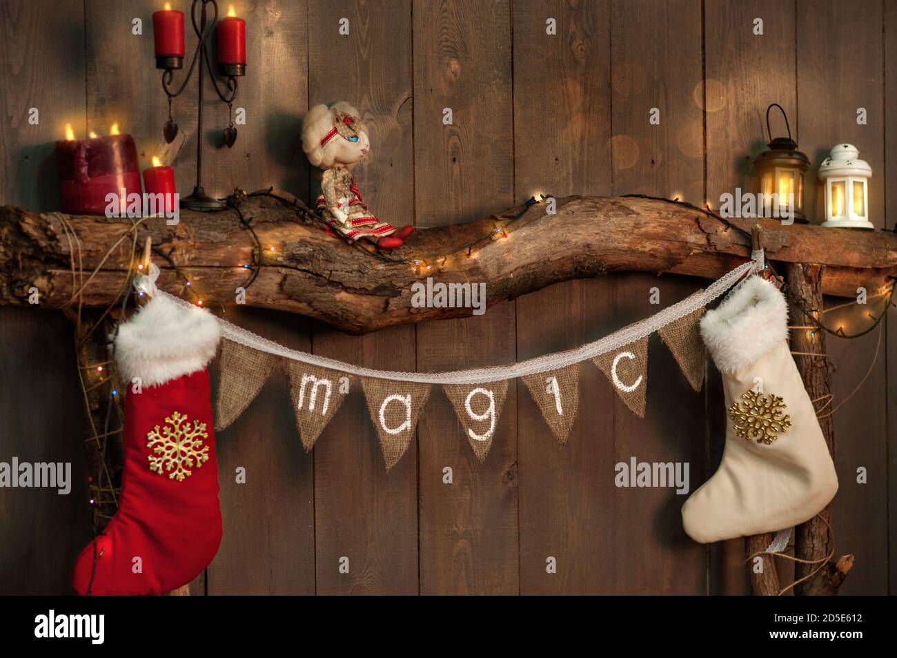 Su un camino in legno fatto di vecchi tronchi, vi è un tratto di bandiere con l'iscrizione Magic, calze bianco-rosso per i regali di Babbo Natale appendere sul Foto Stock