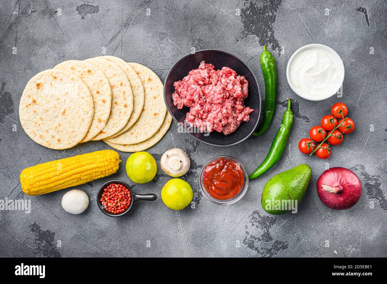 Tacos messicani organici crudi ingredienti con patatine di tortilla,  avocado, salsa, peperoncino e carne. Su sfondo grigio in cemento, vista  dall'alto Foto stock - Alamy