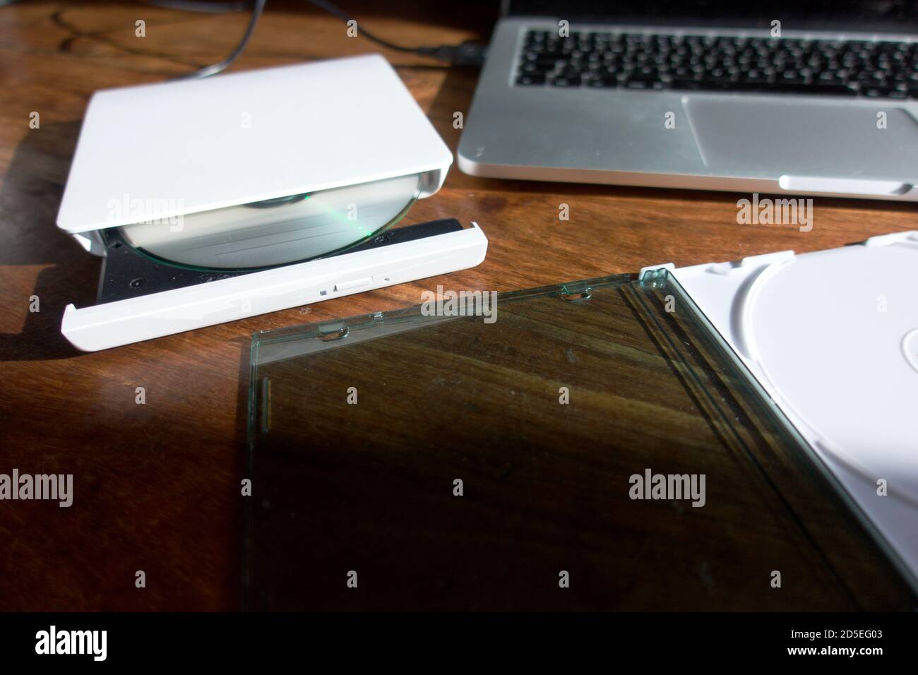 Un lettore/masterizzatore CD/DVD esterno collegato a un computer portatile tramite USB - utilizzato per leggere o scrivere su CD e DVD. Foto Stock