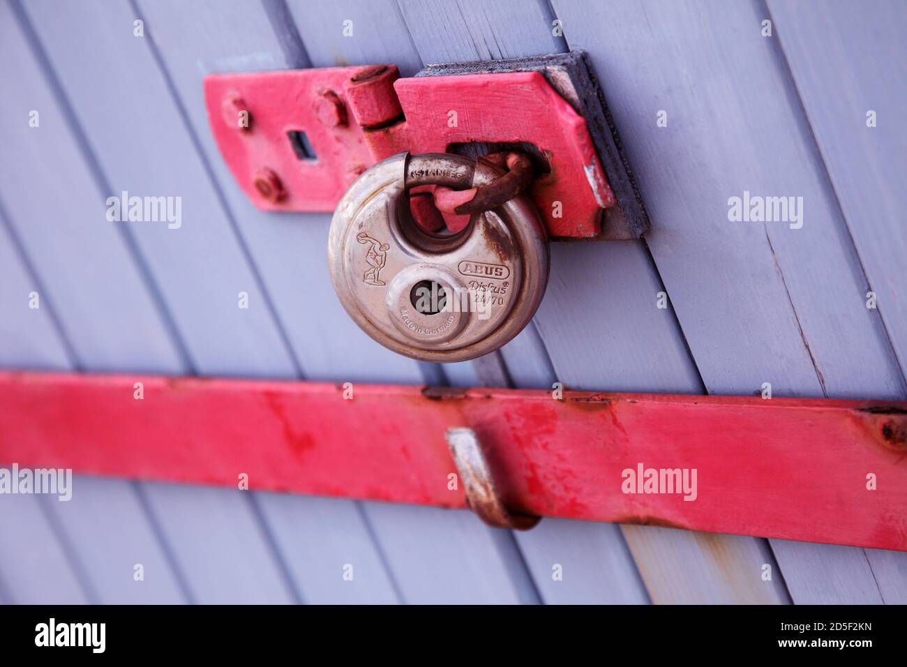 Lucchetto in argento su porta viola blu con barra di sicurezza rossa. Porte doppie con lucchetto. Foto Stock