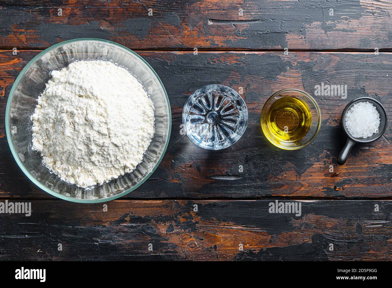 Ingredienti per l'impasto, l'acqua dell'olio di farina e il sale su fondo  di legno Foto stock - Alamy