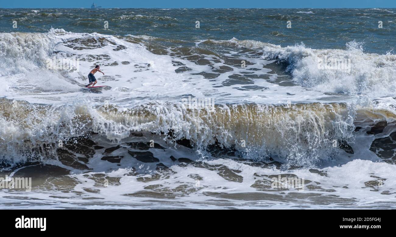 Il surfista della Florida che cavalcano un'onda sopraelevata come un'onda di Nor'easter si combina con l'uragano Teddy Swells per produrre il surf grande ai poli a Jacksonville, Florida. Foto Stock