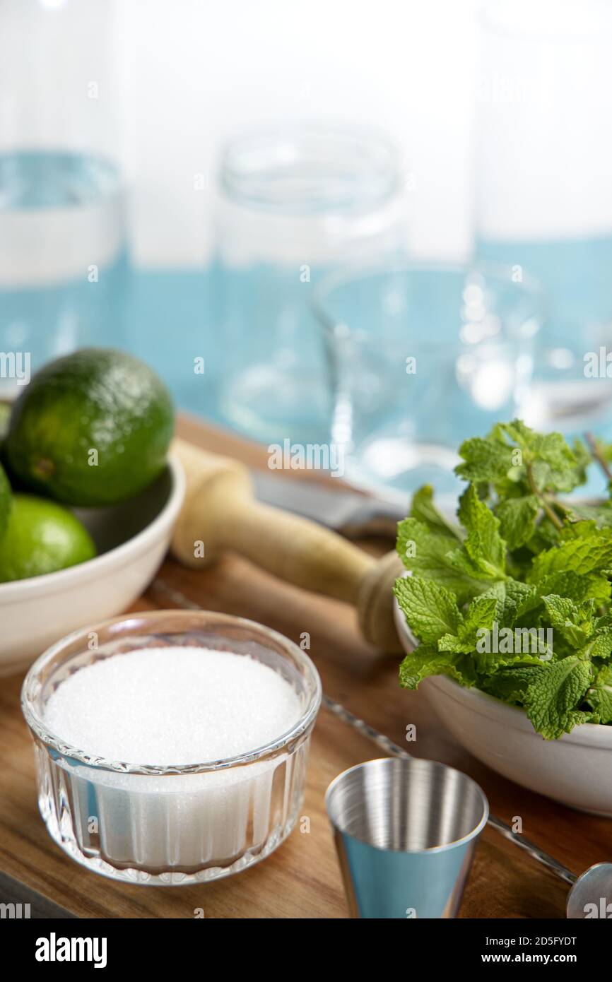Ingredienti e utensili da cocktail Mojito su tagliere in legno. Tabella blu e sfondo bianco Foto Stock