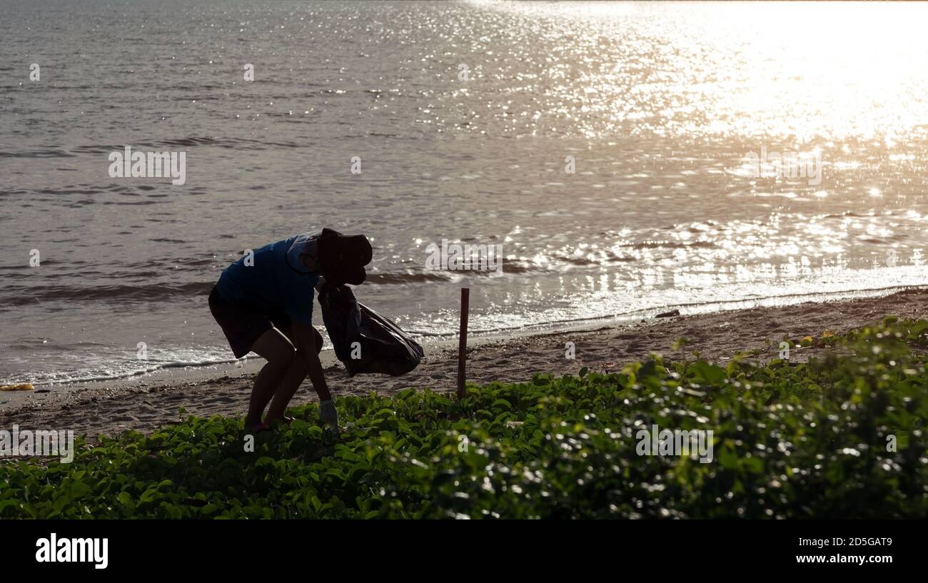 volontariato pulizia mare spiaggia dopo coronavirus pandemia con maschera e. guanto Foto Stock