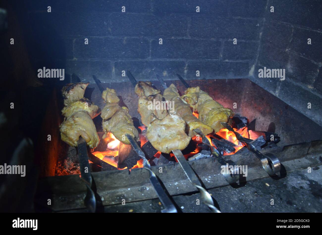 Grigliare la carne cruda con le mani femminili sulla griglia all'aperto. Cucina barbecue di carne su griglia al carbone al picnic. Sgranchite il kebab alla griglia durante la festa del barbecue Foto Stock