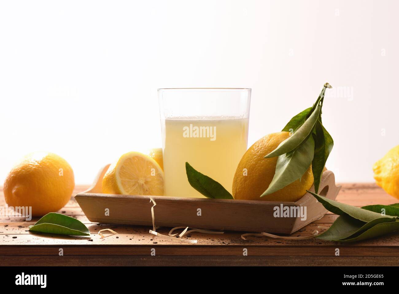 Spremuta fresca su un tavolo di legno pieno di limoni bianco fondo isolato. Vista frontale. Composizione orizzontale. Foto Stock