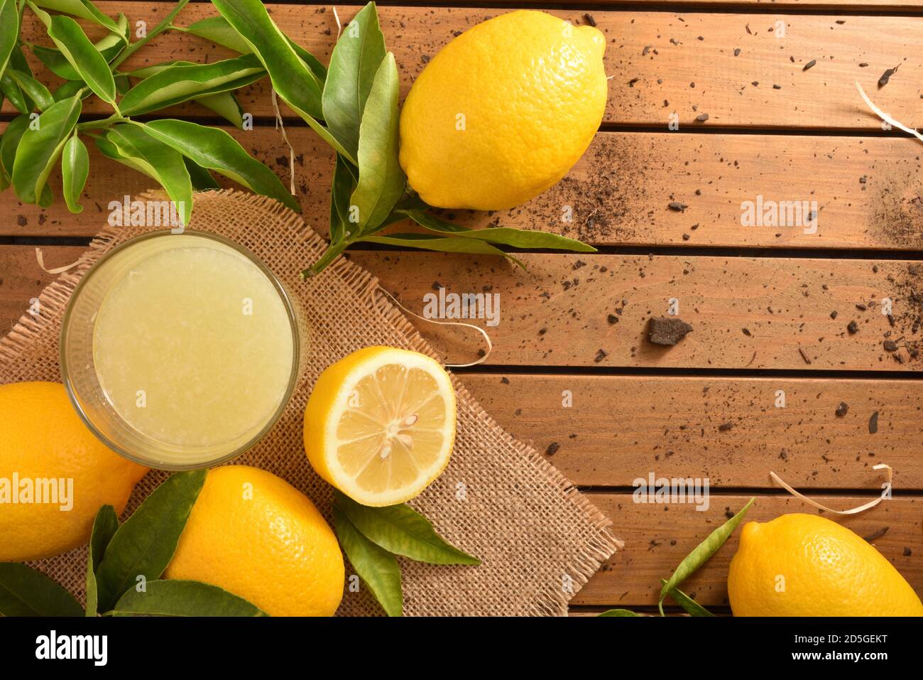 Spremuta fresca su un tavolo di legno su una tela piena di limoni. Vista dall'alto. Composizione orizzontale. Foto Stock