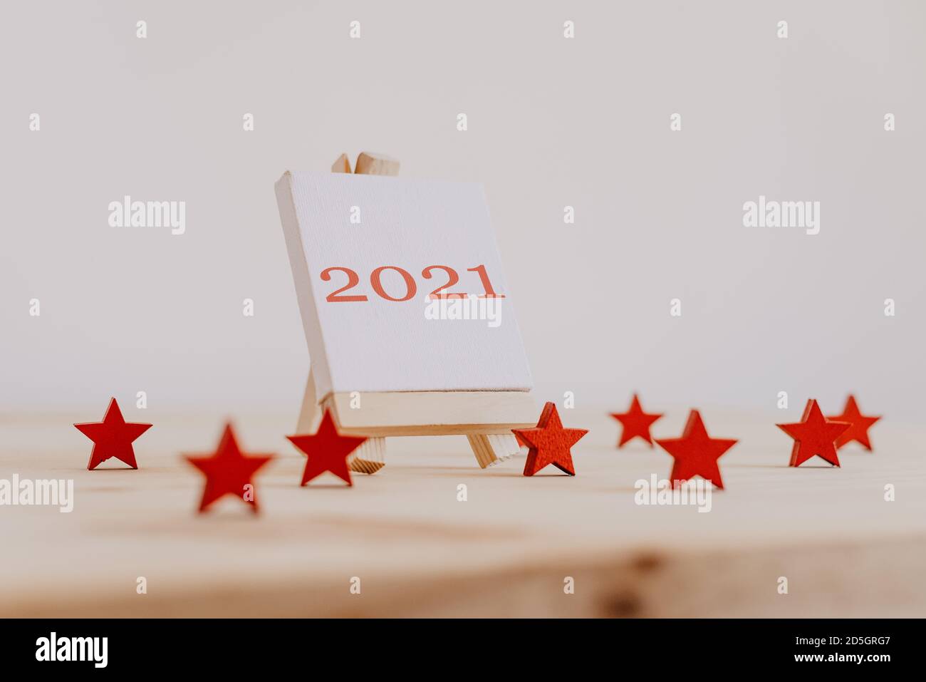 2021 scritto in rosso sulla tela di un cavalletto di pittura con stelle decorative in legno rosso. Foto Stock