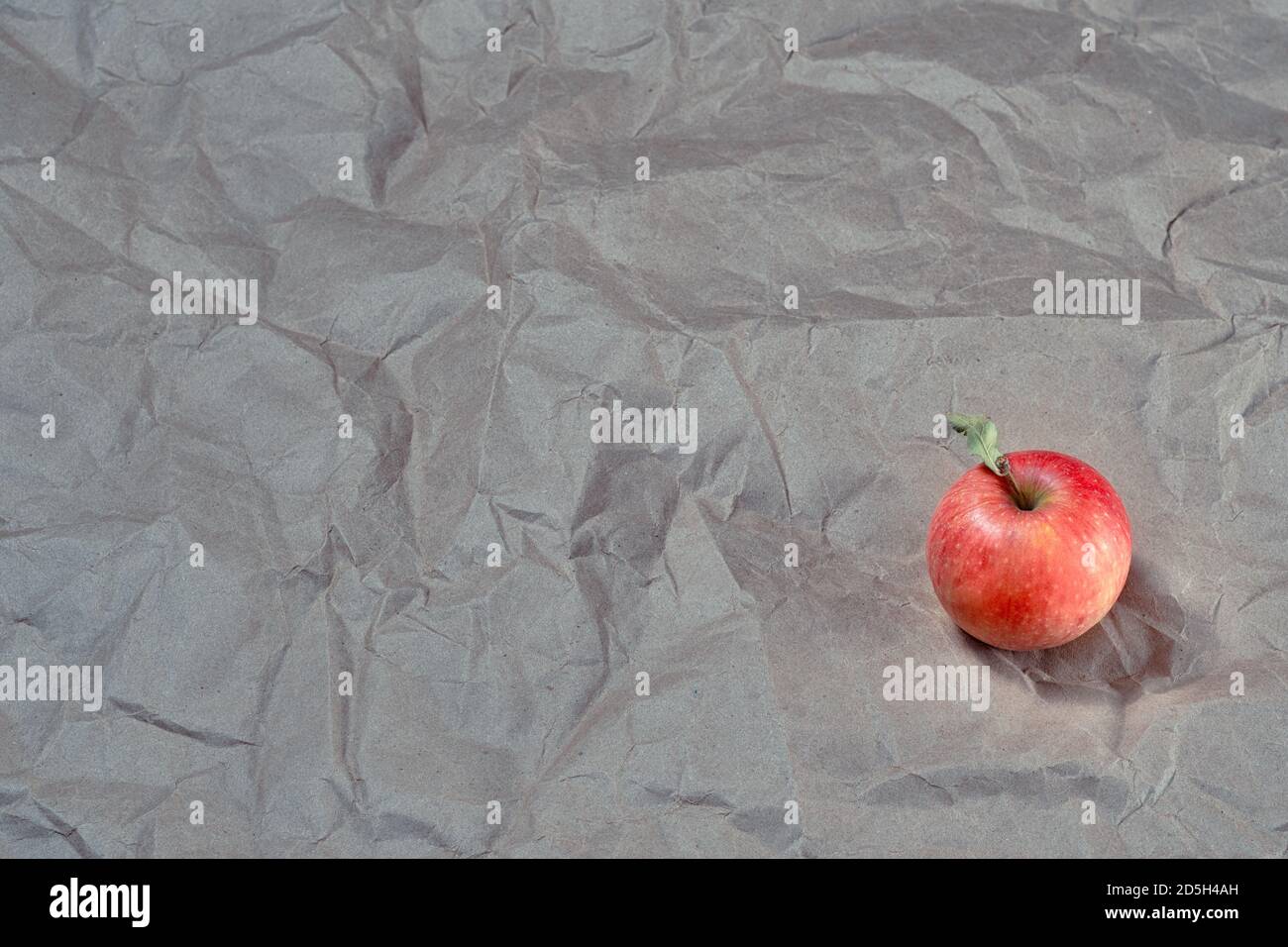 una mela matura fresca su fondo naturale di carta artigianale grigia vendemmia autunnale Foto Stock