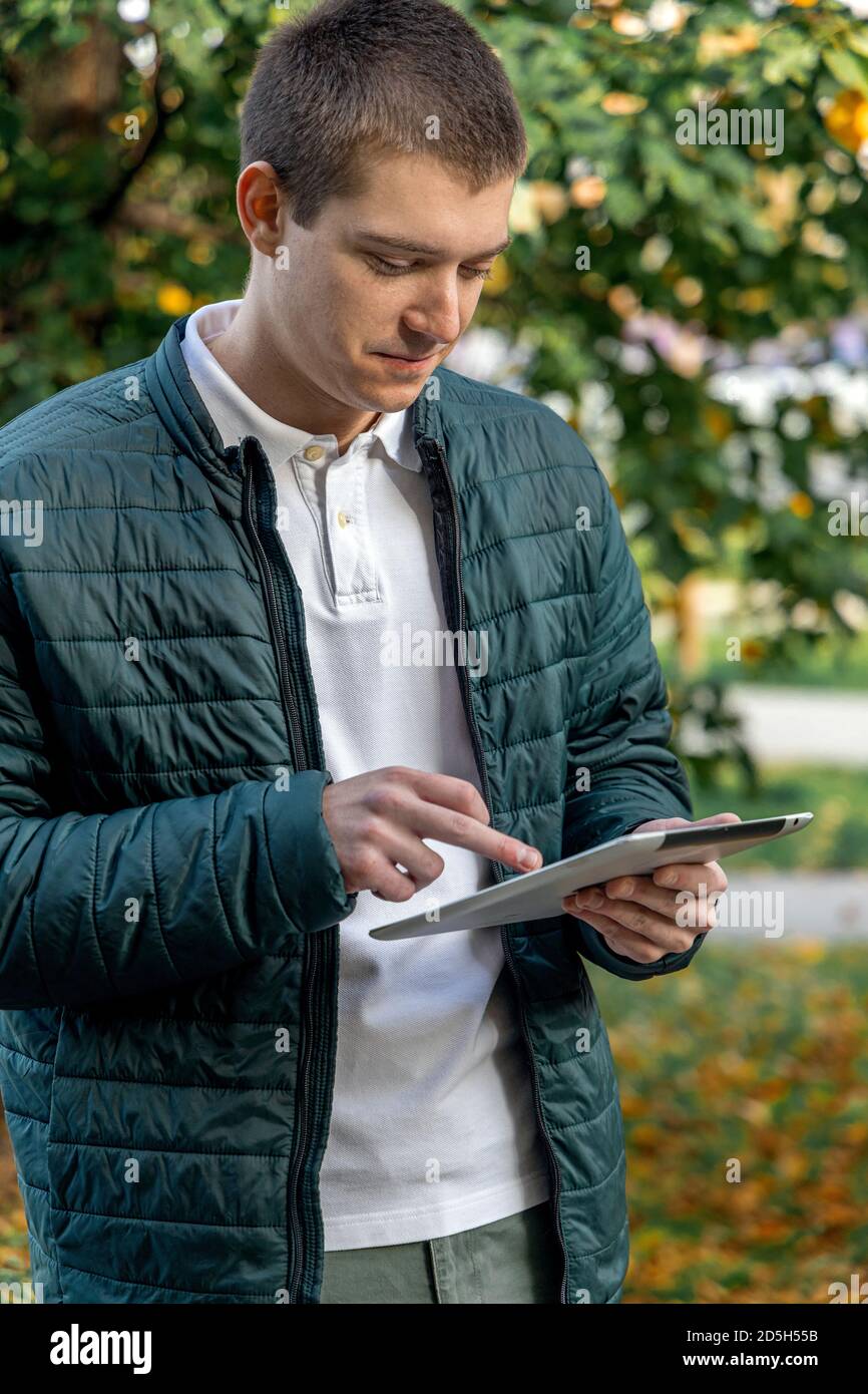 Giovane uomo che naviga in Internet su un tablet all'aperto Foto Stock