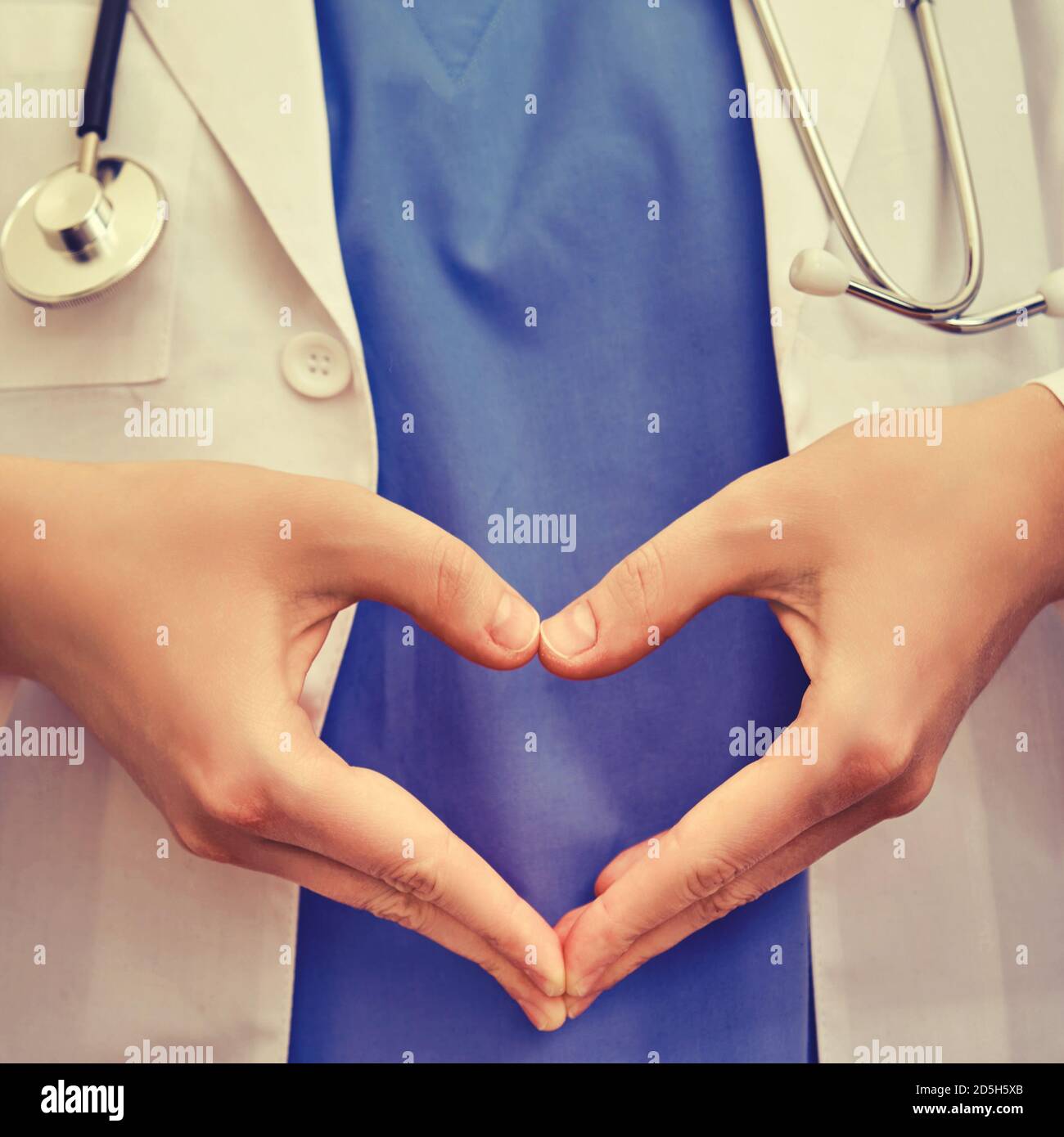 Infermiere mostra un gesto a forma di cuore, primo piano. Dottore ha piegato le dita sotto forma di cuore, sfondo blu Foto Stock