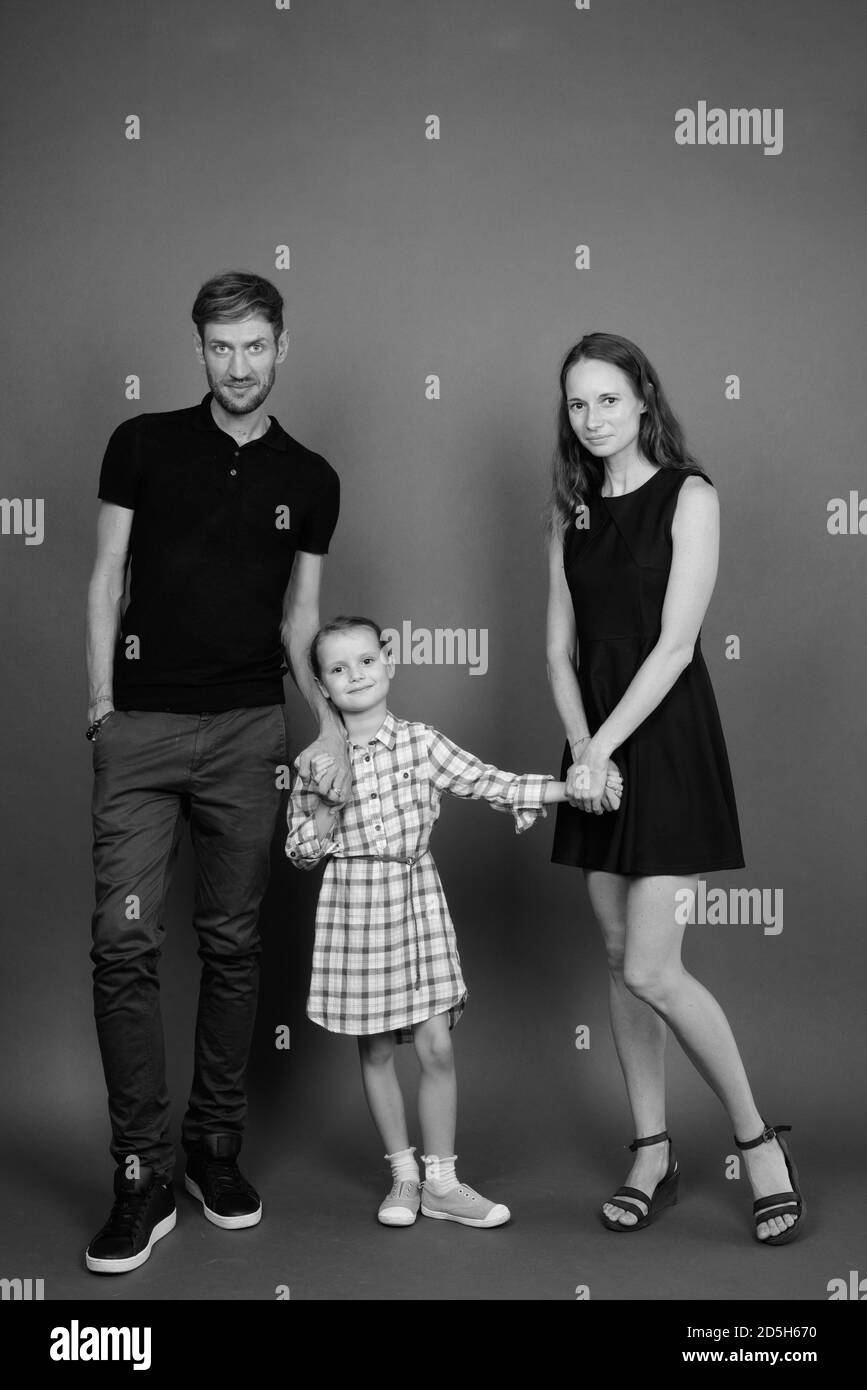 Giovane famiglia felice legare insieme contro lo sfondo grigio Foto Stock