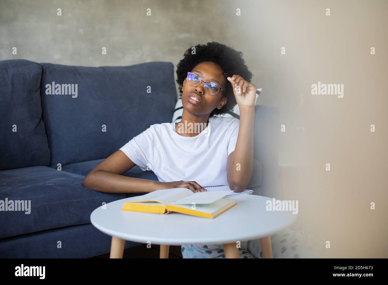 African American ragazza scrive in un notebook in un accogliente camera Foto Stock