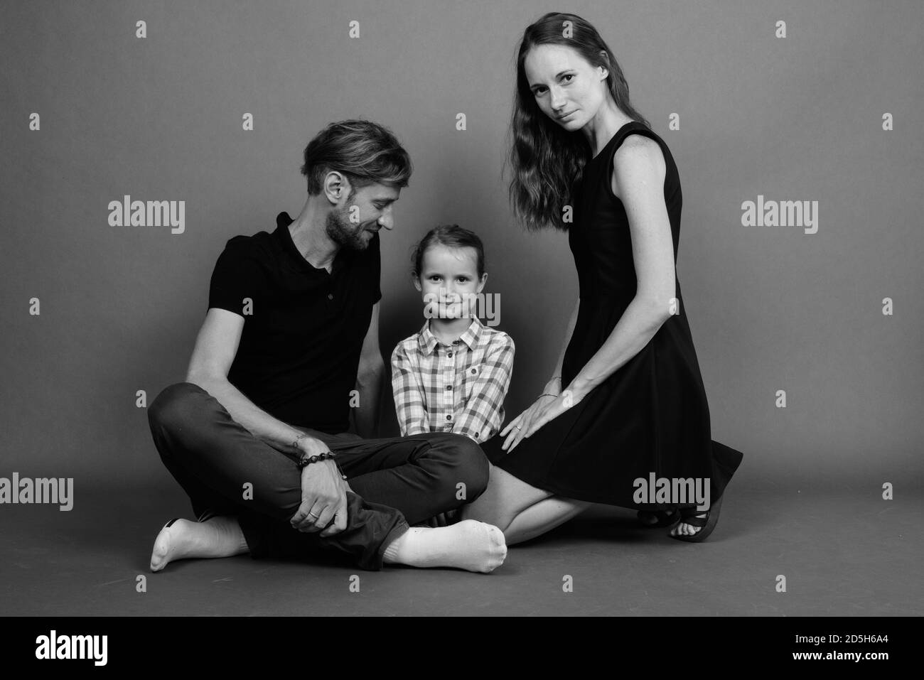 Giovane famiglia felice legare insieme contro lo sfondo grigio Foto Stock