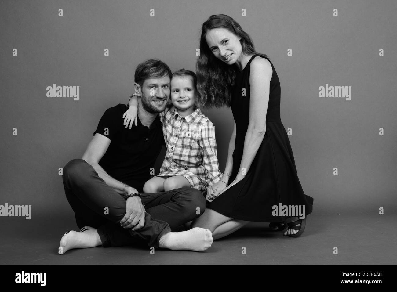 Giovane famiglia felice legare insieme contro lo sfondo grigio Foto Stock