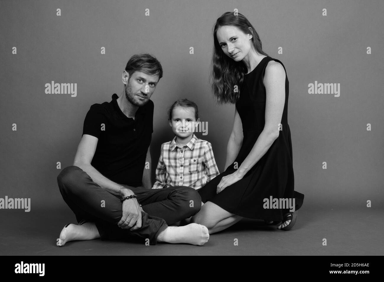 Giovane famiglia felice legare insieme contro lo sfondo grigio Foto Stock