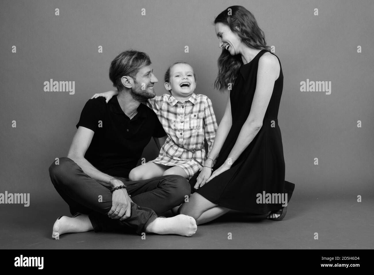 Giovane famiglia felice legare insieme contro lo sfondo grigio Foto Stock