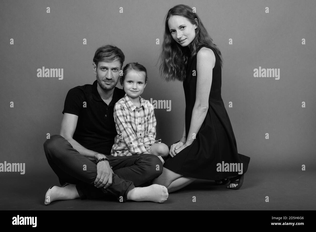 Giovane famiglia felice legare insieme contro lo sfondo grigio Foto Stock