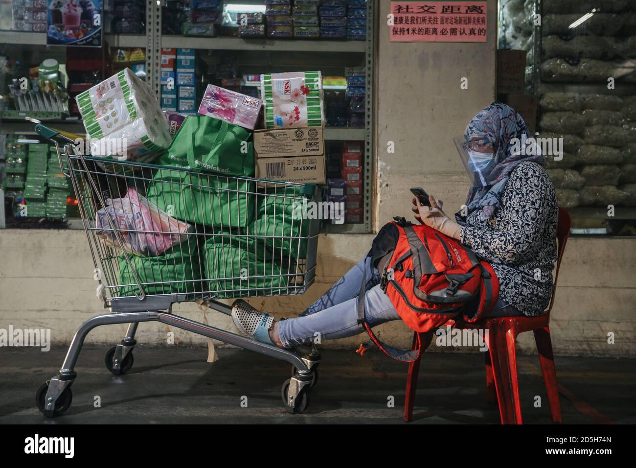 Una donna con un carrello pieno di generi alimentari mentre attende che il suo veicolo arrivi seguendo un CMCO (Conditional Movement Control Order) reimposto dal governo malese per due settimane, quando i casi si impiccano tra le preoccupazioni del coronavirus (Covid-19). Foto Stock