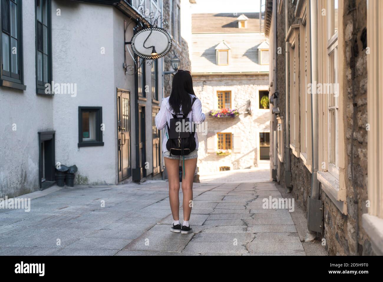 Una donna cinese che cammina lungo uno stretto vicolo vicino a Place paris nella vecchia zona portuale della città di Quebec, Canada. Foto Stock