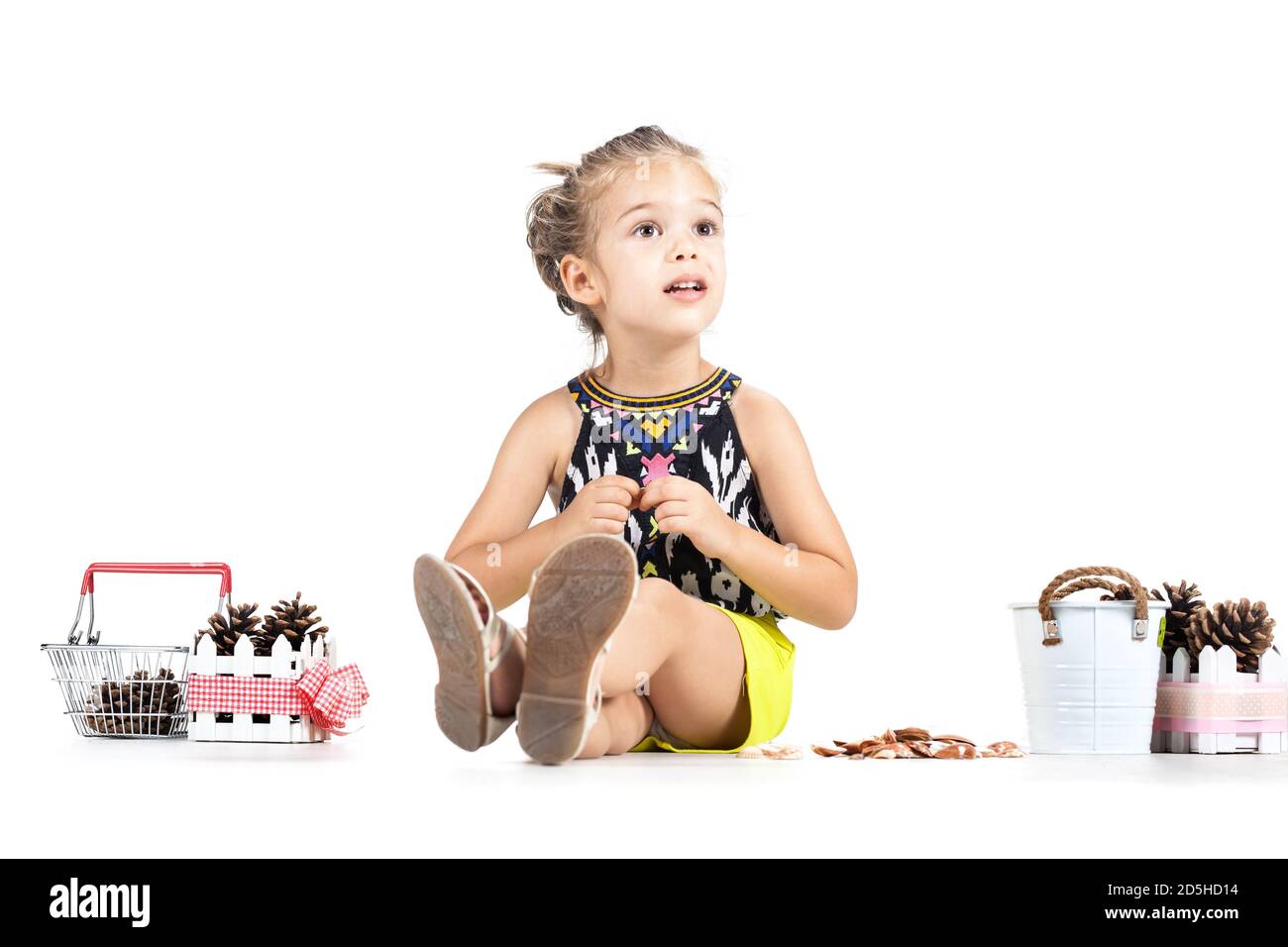 piccola ragazza caucasica che gioca con i pinecones Foto Stock