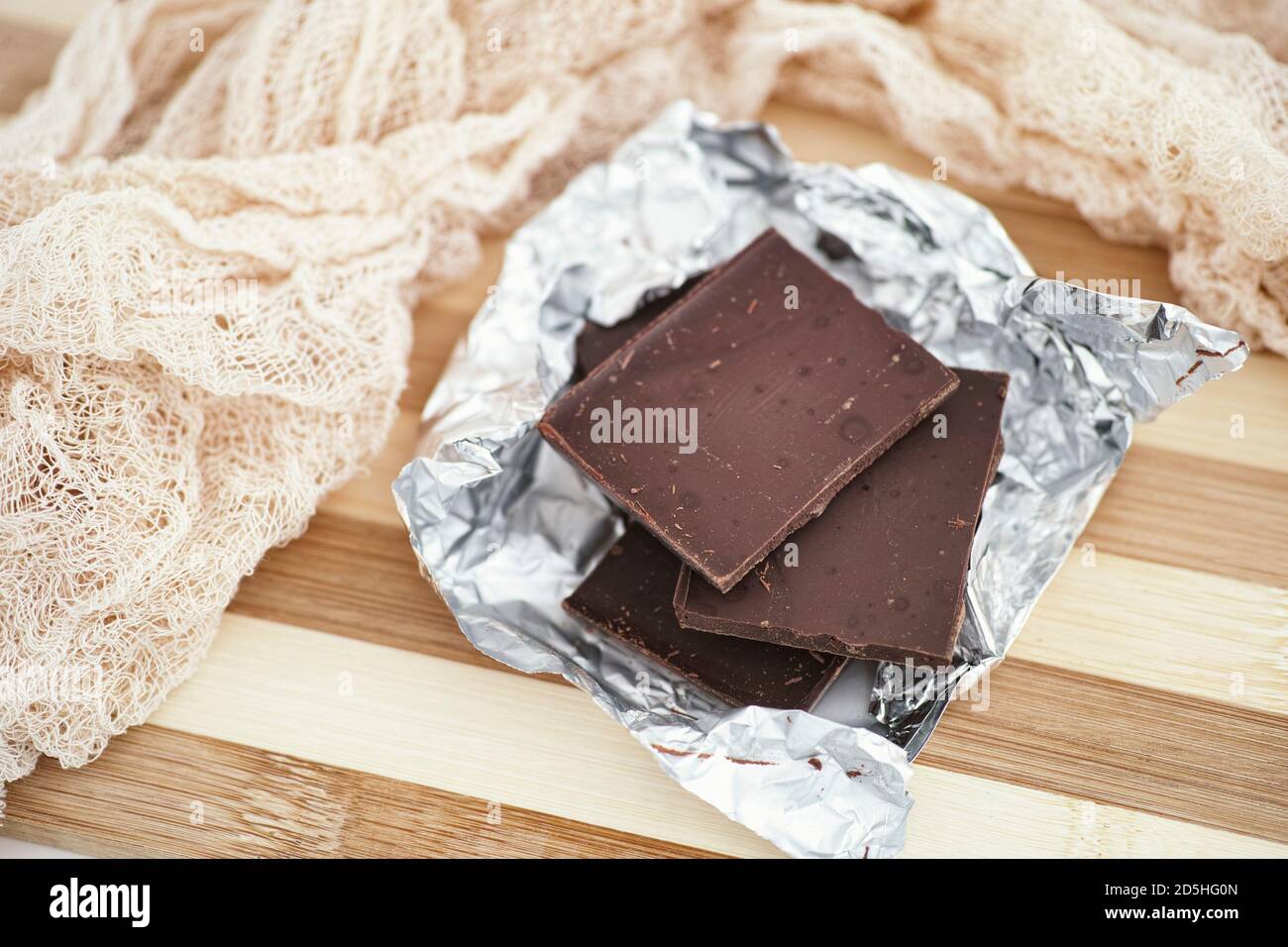 Pezzi di cioccolato scuro rotto in foglio di imballaggio. Primo piano. Foto Stock