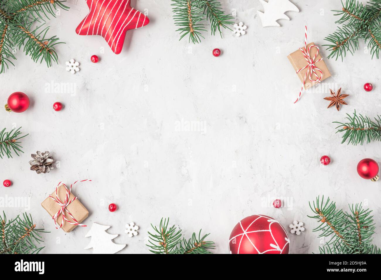 Natale o Felice anno nuovo background. Cornice in rami di abete, decorazioni per le vacanze e scatole regalo su fondo in cemento. Posa piatta. Vista dall'alto Foto Stock